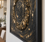 Close-up of framed stone mosaic wall art with gold flecks and spiral ring texture