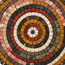 Close-up handmade stone mosaic wall art with concentric rings of multicolor stones