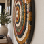 Round handmade stone mosaic wall art with concentric earth-tone rings, side view