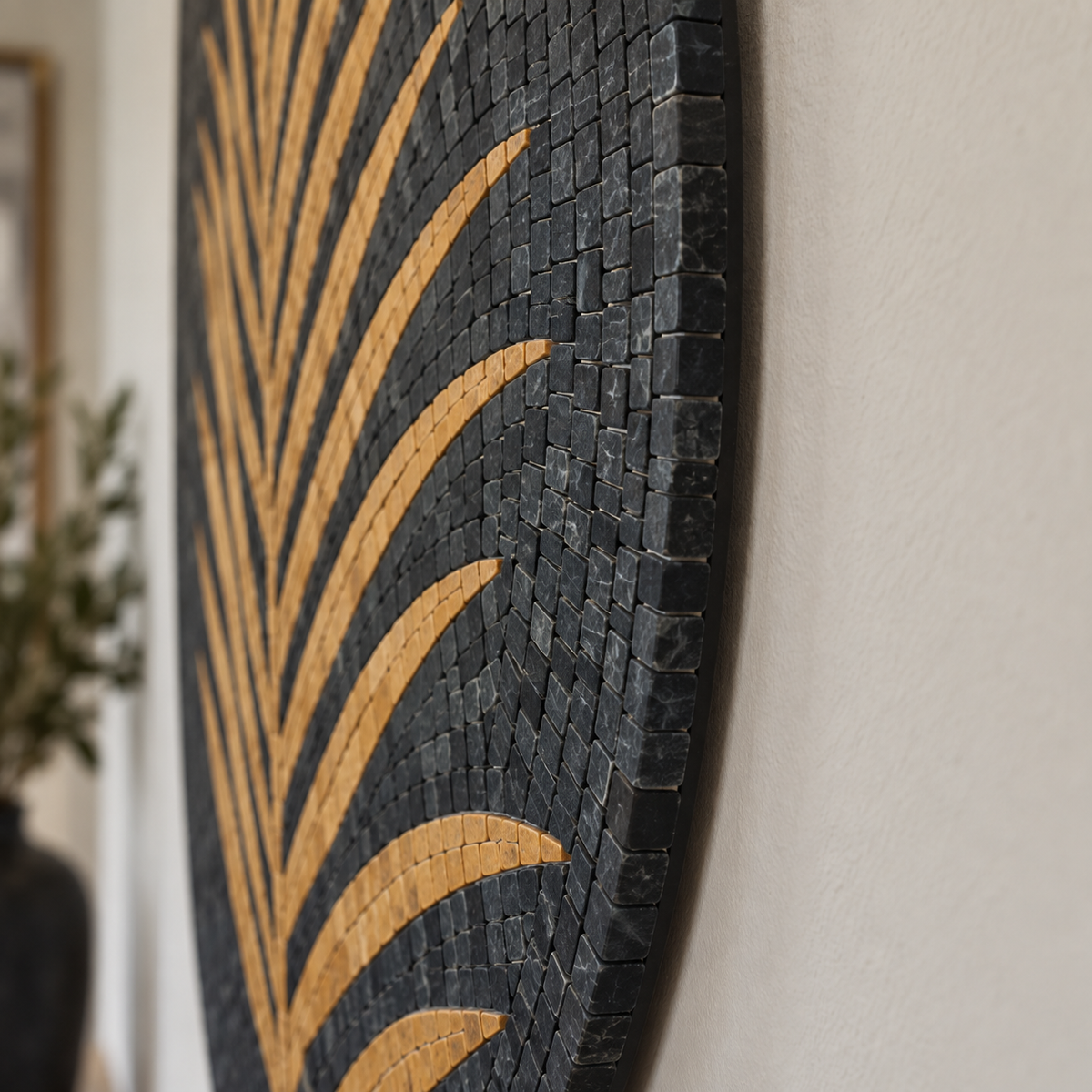 Round stone mosaic wall art with dark blue-black palm frond lines in tan.