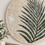 Large round stone mosaic wall art showing dark green palm leaf lines on cream tiles