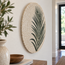 Round stone mosaic wall art featuring a dark green palm leaf motif on cream tiles