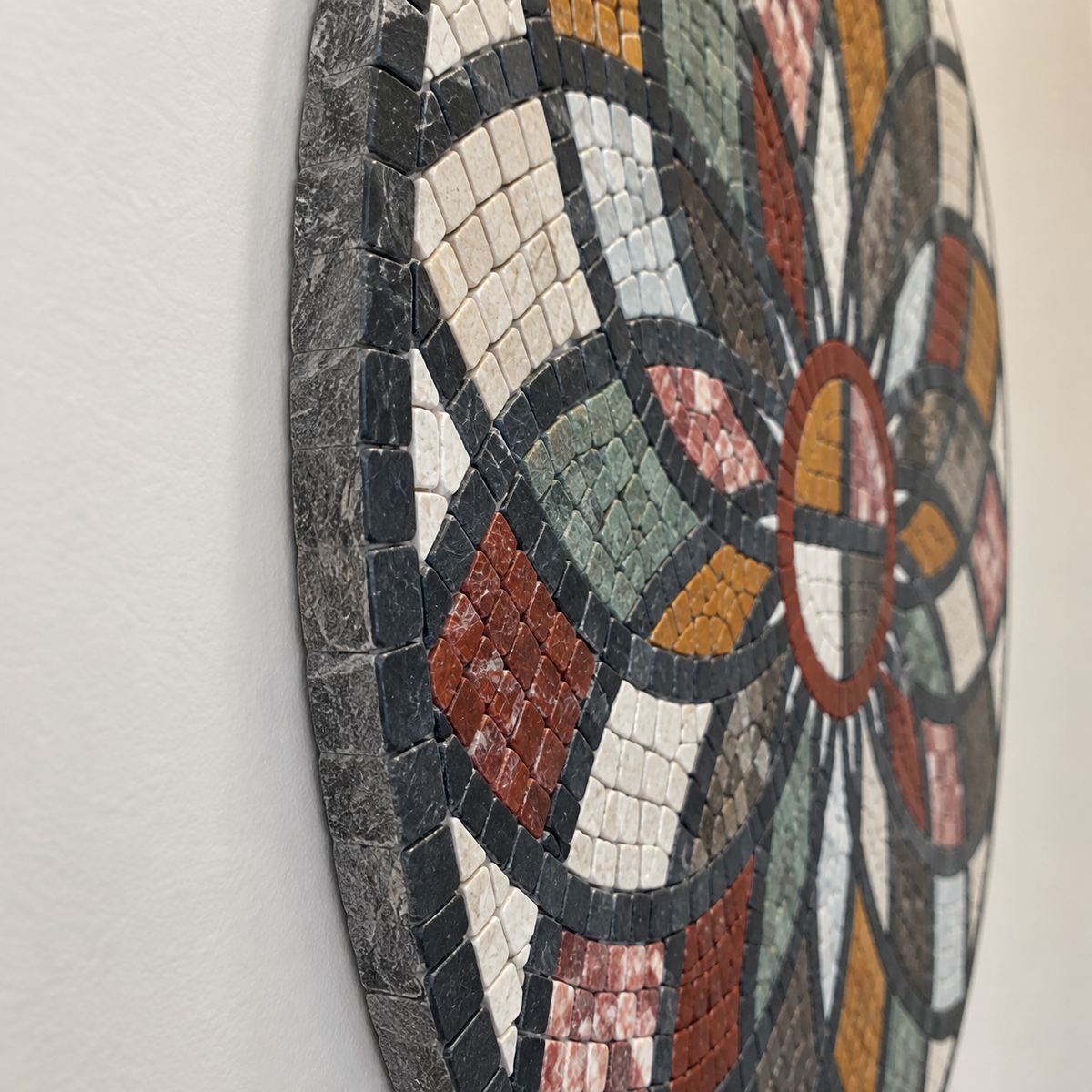Close-up of round stone mosaic wall art with curved multicolor tile segments
