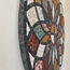 Close-up of round stone mosaic wall art with curved multicolor tile segments