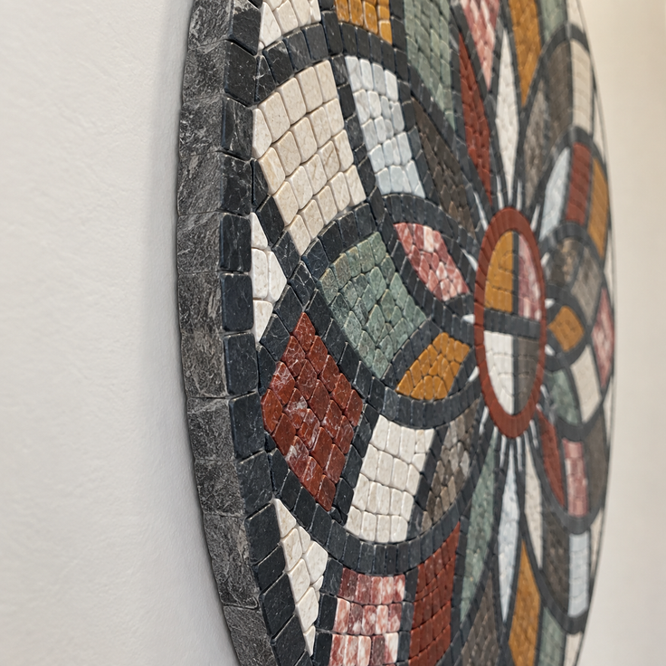 Close-up of round stone mosaic wall art with curved multicolor tile segments