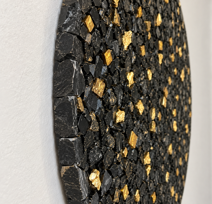 Handmade stone mosaic wall art close-up with black tiles and gold flecks