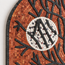 Close-up stone mosaic with orange tiles, black branches, and a white moon center