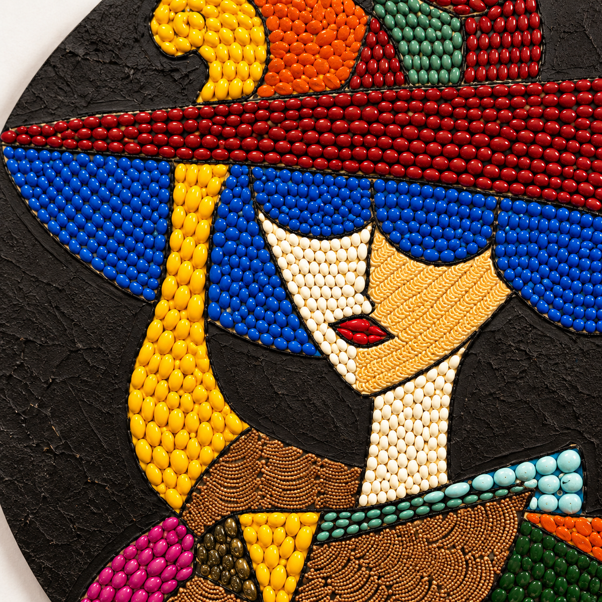 Close-up mosaic glass detail of woman’s hat, face, and fan in blue, yellow, and red