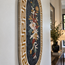Oval floral mosaic wall hanging with Greek key border and black background.