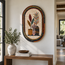 Oval stone mosaic wall art with plant stems and vases, arched multicolor border