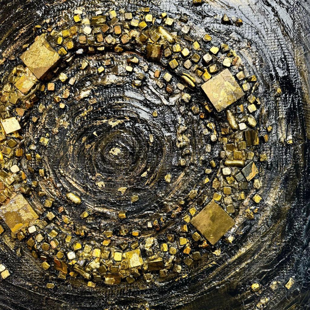 Gold and black stone mosaic wall art with circular swirl pattern, close-up detail