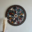Round stone mosaic floral rosette wall art with multicolor tiles; feather decor at bottom left