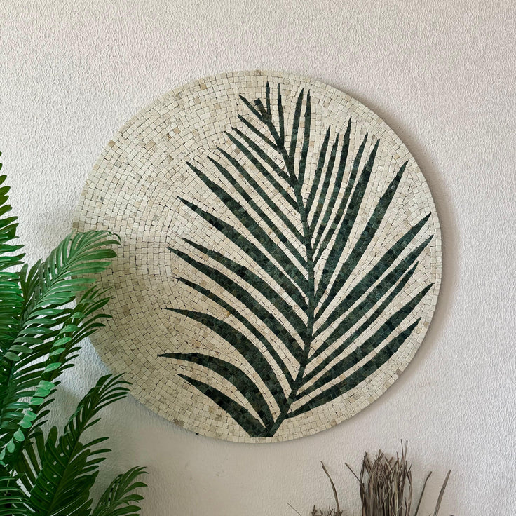 Close-up round stone mosaic wall art with cream and dark green palm leaf design