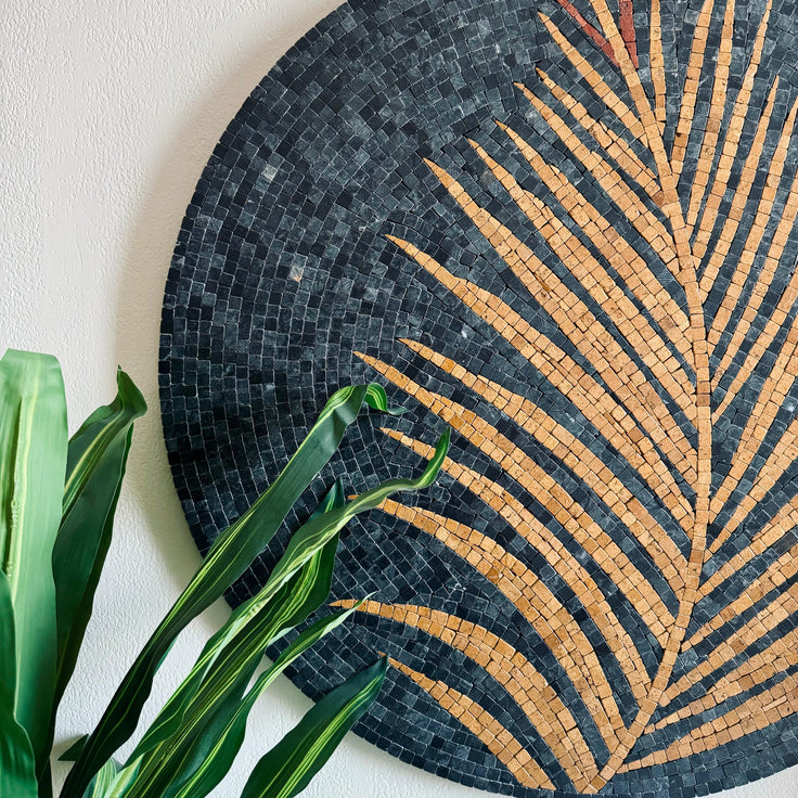 Round mosaic palm frond wall art with dark blue and golden tan tile rays.
